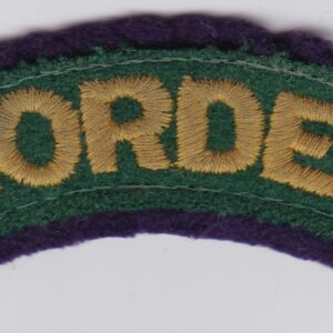 A green and purple border patch on a white surface.