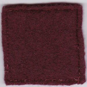 A burgundy felt patch on a white surface.