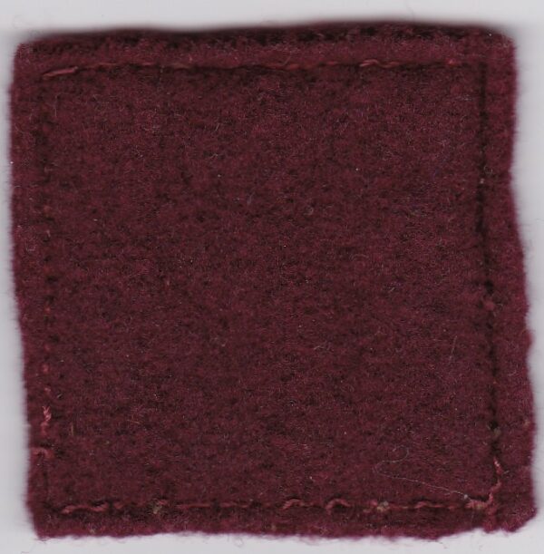 A burgundy felt patch on a white surface.